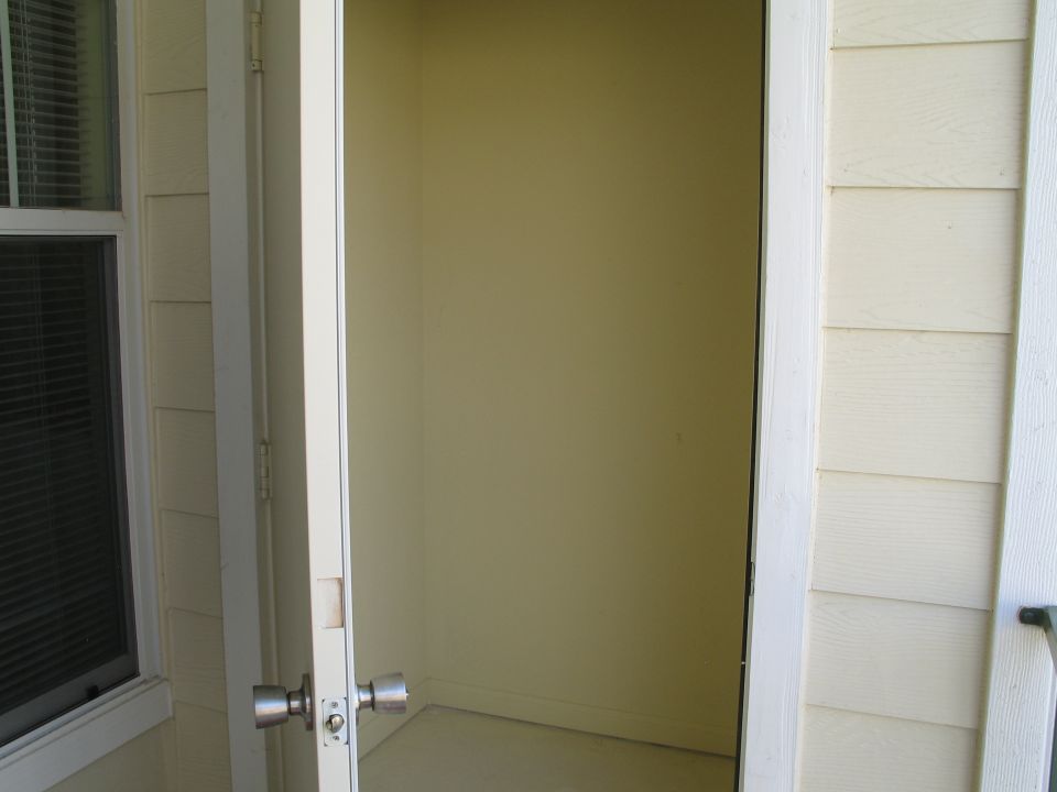 Open exterior door showing empty olive-painted closet on cream-sided house