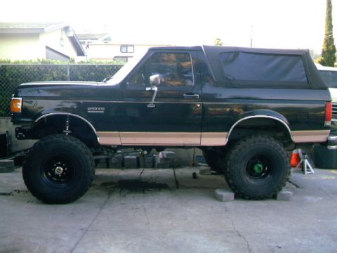 1989 Ford Bronco - This lifted 1989 Ford Bronco features a two-tone paint scheme with tan trim and a black soft top.