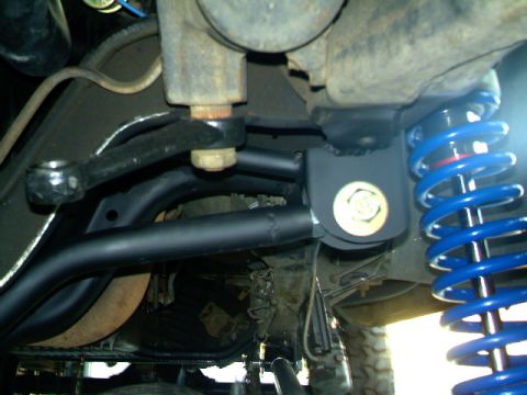 1989 Ford Bronco - The underside of a vehicle shows modified suspension parts, including a bright blue coilover shock absorber.