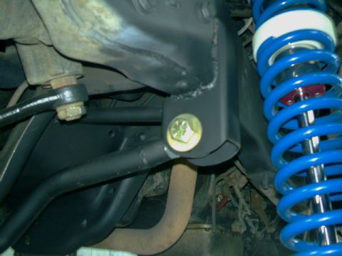 1989 Ford Bronco - Close-up view of suspension components, including a blue coilover shock and a black bracket.