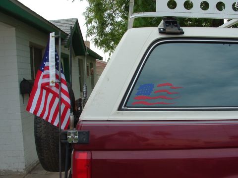 1990 Ford Bronco - Pickup truck rear with American flag sticker and spare tire carrier mounted flag.