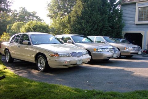 1996 Mercury Grand Marquis - Three large sedans are parked in a driveway in front of a house and garage.