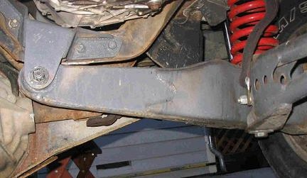 1984 Ford Bronco - Close-up view of the undercarriage of a vehicle, focusing on suspension parts and a red coil spring.