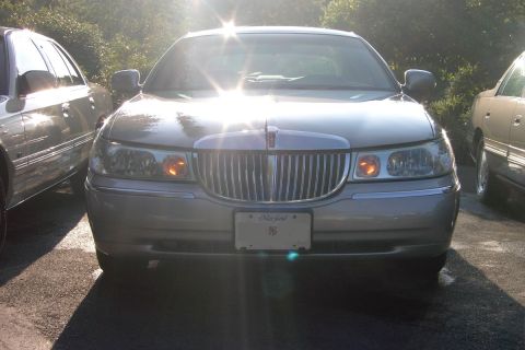 1996 Mercury Grand Marquis - A silver Lincoln Town Car is parked between two other vehicles, facing the camera.