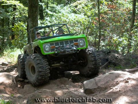 1996 Ford Bronco - This modified Ford Bronco is tackling a challenging off-road course in the woods.