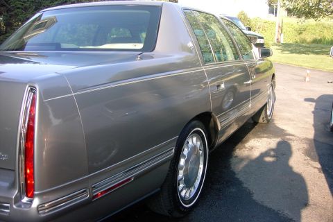 1996 Mercury Grand Marquis - The rear passenger side of a gray Cadillac sedan is visible, parked outdoors on a paved surface.