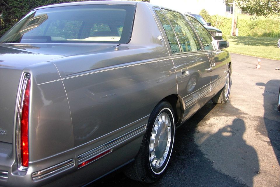 Rear quarter view of a champagne gray four-door sedan on a driveway