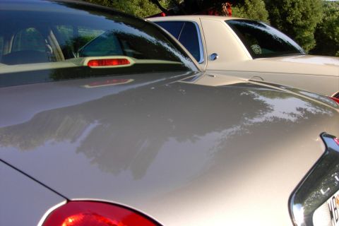 1996 Mercury Grand Marquis - A tan sedan is parked next to a cream-colored vehicle, with trees in the background.