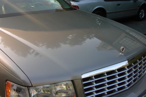 1996 Mercury Grand Marquis - Close-up of a car's front grille and hood, with a second vehicle in the background.