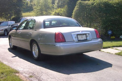 1996 Mercury Grand Marquis - A tan Lincoln Town Car is parked on a driveway, with another car visible in the background.