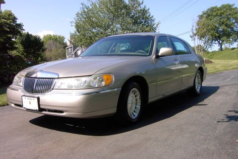1996 Mercury Grand Marquis - This tan sedan, viewed from the front three-quarter angle, appears to be a 1998 Lincoln Town Car, not the 1996 Mercury Grand Marquis listed.