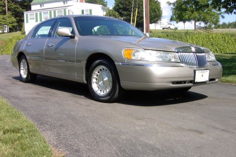 1996 Mercury Grand Marquis - This 1998 Lincoln Town Car is parked on a driveway with a house and trees in the background.