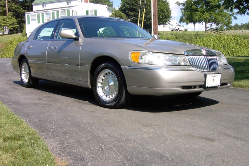 Gold Lincoln Town Car sedan, front three-quarter view, parked on driveway