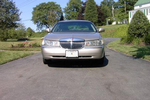 1996 Mercury Grand Marquis - A tan Lincoln Town Car is parked on a driveway in front of a house on a sunny day.