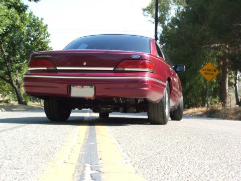 1992 Ford Crown Victoria - Rear view of a red 1992 Ford Crown Victoria on a road with a narrow bridge sign.