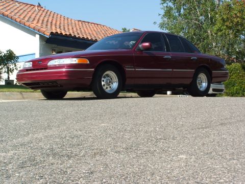 1992 Ford Crown Victoria - This maroon sedan is parked in front of a house on a sunny day.