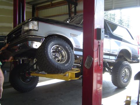 1989 Ford Bronco - Ford Bronco undergoing service on a lift, highlighting its suspension and lifted stance.