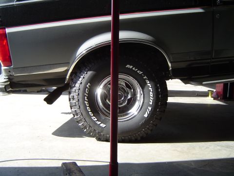 1989 Ford Bronco - The rear fender and tire of a truck are visible, with "Mud-Terrain T/A" text on the tire.