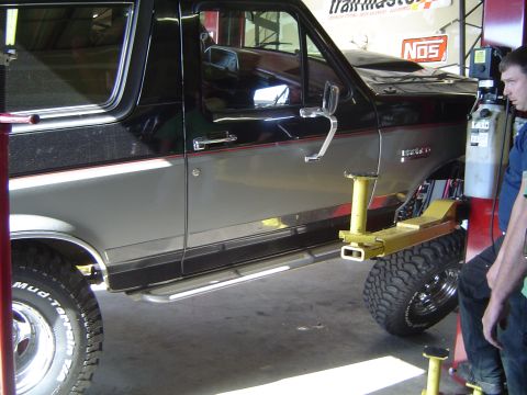 1989 Ford Bronco - A 1989 Ford Bronco is shown on a lift in a garage, possibly for rear spring work.