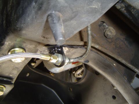 1989 Ford Bronco - Underside view of vehicle suspension showing brake line connection and metal components.