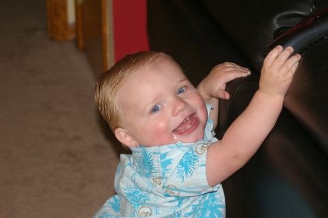 1998 Jeep TJ - A baby smiles while reaching for a black object, with a watermark for Supermotors.net visible.