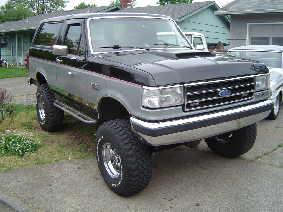 Black-and-silver Ford Bronco SUV, lifted, front three-quarter in a driveway
