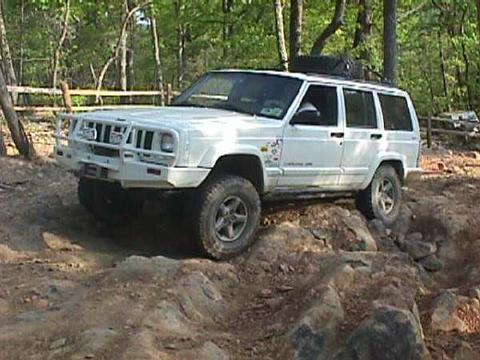 1996 Ford Bronco - White Jeep Cherokee XJ navigates a rocky trail with a custom front bumper.
