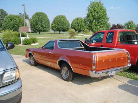 1972 Ford Ranchero - The 1972 Ford Ranchero is seen from a rear-right angle, parked on a driveway next to a red pickup truck.