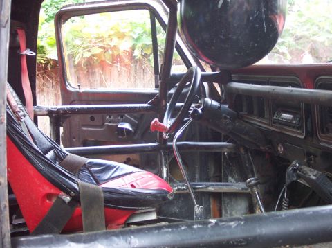1978 Ford Bronco - The interior of a vehicle shows a rollcage and racing seat, suggesting modifications for off-road use.
