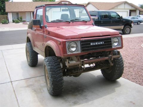 1987 Suzuki Samurai - This red 1987 Suzuki Samurai features a lifted suspension and aggressive off-road tires, ready for adventure.