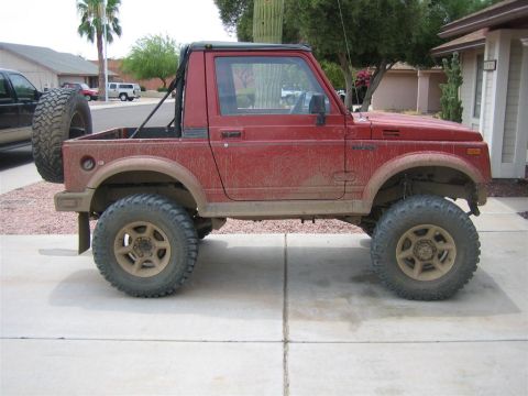 1987 Suzuki Samurai - Side view of a red 1987 Suzuki Samurai modified with off-road tires.