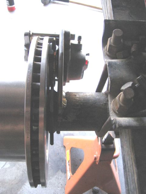 1994 Ford Bronco - Close-up of a vehicle's rear axle disc brake assembly supported by a jack stand.