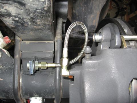 1994 Ford Bronco - Detail of a vehicle's disc brake caliper and associated brake line assembly.