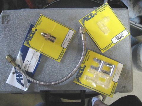 1994 Ford Bronco - Various brake line components, including fittings and a braided hose, are displayed on a toolbox.