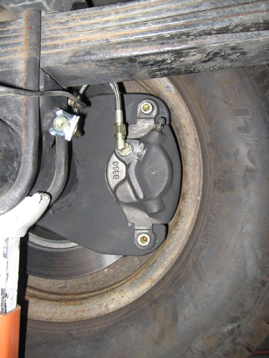 Disc brake caliper and rotor inside a wheel with braided brake hose, checking tire clearance
