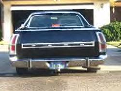 1972 Ford Ranchero - The rear of a dark-colored Ford Ranchero is parked in front of a garage door.