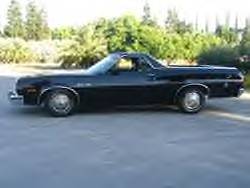 1972 Ford Ranchero - A black 1972 Ford Ranchero pickup truck is shown from the side, parked outdoors with a line of trees behind it.