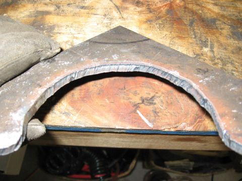 1994 Ford Bronco - A metal bracket with rough cut edges is positioned on a wooden surface.
