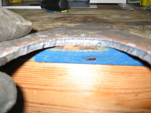 1994 Ford Bronco - Metal component with visible machining marks, placed on a wooden workbench.