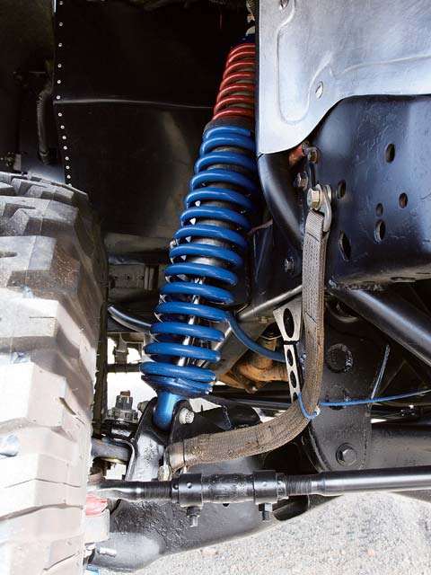 1984 Ford Bronco - Vehicle suspension detail showing a blue coilover shock and linkage.