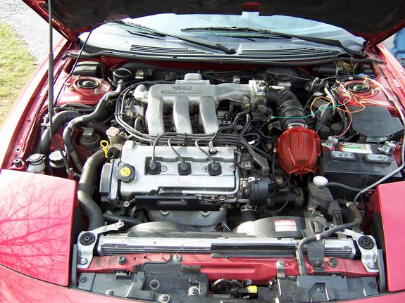 Open engine bay of a red car showing a V6 engine with red aftermarket cone air filter
