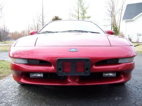 1996 Ford Probe - Frontal view of a red Ford Probe, displaying its distinctive headlights and Ford emblem.