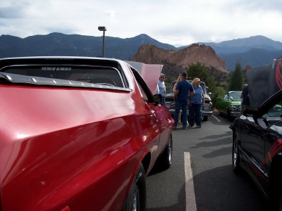 1972 Ford Ranchero - A red 1972 Ford Ranchero is parked at a car show with other vehicles and people, mountains in the background.