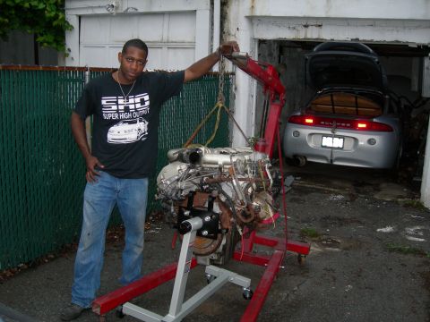 1992 Ford Taurus - A person in an 'SHO Super High Output' T-shirt stands beside a Yamaha-built Ford SHO V6 with its ribbed aluminum intake manifold, mounted o…