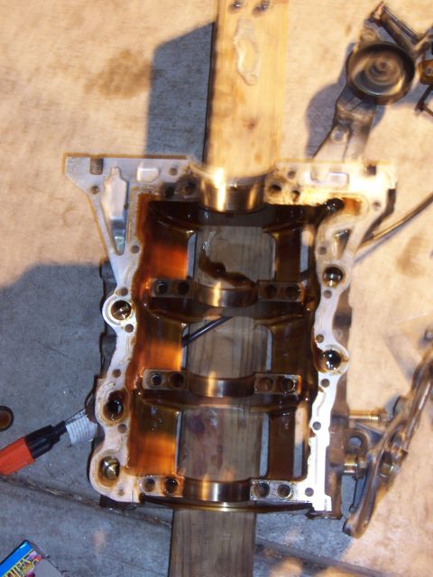 1996 Ford Probe - Close-up of an engine block part, showing internal components and oil staining. The part is supported by wooden beams.