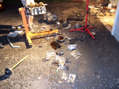 1996 Ford Probe - Engine components are laid out on the ground next to an engine stand, suggesting a repair or rebuild process.
