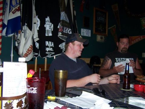 1995 Ford Bronco - Two men are seated at a bar, with drinks and various items on the table in front of them.