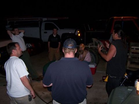 1995 Ford Bronco - Several people stand around vehicles in a dimly lit outdoor area at night.