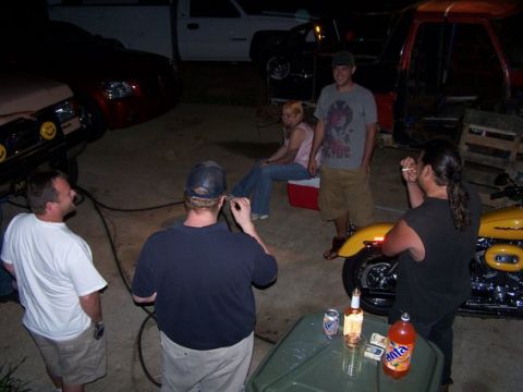 1995 Ford Bronco - Several people and vehicles are visible in this nighttime scene, with drinks on a table.
