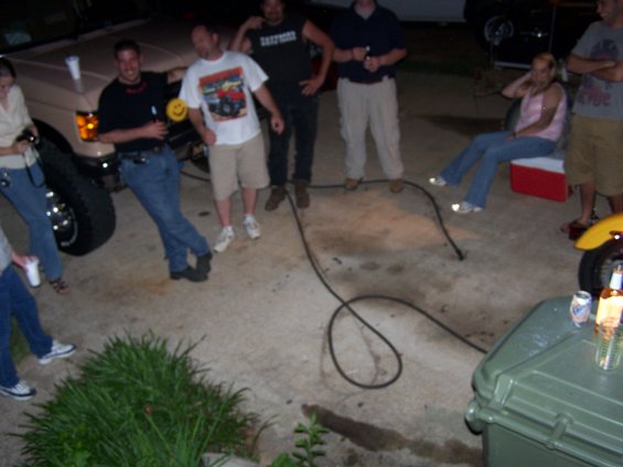Tan SUV with people standing around it, some holding drinks